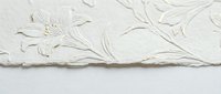 Elegant white embossed floral pattern on handmade paper with decorative deckled edges for luxury stationery and wedding invitations.