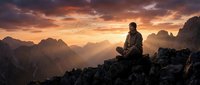 Young man meditating on mountain peak at sunset with dramatic orange sky and layered mountain ranges creating peaceful spiritual atmosphere for wellness content.