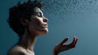 Young African American woman with curly hair dissolving into particles against blue background, holding hand up in spiritual contemplative pose.