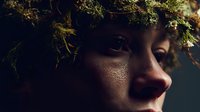 Young woman with moss crown in mystical forest light creating ethereal nature portrait for fantasy and environmental themes.