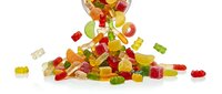 Colorful gummy bears candy spilling from glass jar on white background. Sweet chewy treats in red, green, yellow colors for confectionery and snack concepts.