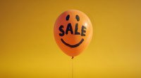 Orange balloon with smiling face and SALE text against vibrant yellow background, creating cheerful shopping promotion atmosphere.
