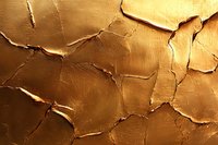 Cracked golden metallic surface with deep fissures and textured pattern creates dramatic light and shadow effect, suitable for luxury design backgrounds.