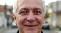 Smiling senior Caucasian businessman with gray hair in outdoor urban setting, professional portrait for corporate and business marketing materials.