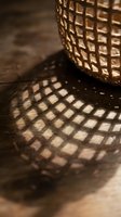 Woven basket casting geometric shadow patterns on wooden surface with warm natural lighting creating artistic home decor atmosphere.