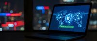 Young male professional working on laptop displaying cybersecurity network interface with glowing digital connections and lock icon, suitable for tech, security, and business concepts.