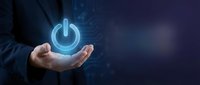Businessman hand holding glowing power button symbol with digital circuit pattern on dark blue background for technology and energy concepts.