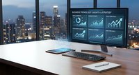 Modern office workspace with computer monitor displaying business analytics dashboard charts and graphs overlooking illuminated city skyline at dusk.