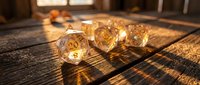 Golden translucent polyhedral dice set on wooden surface with warm sunlight creating dramatic shadows through window for tabletop gaming and role-playing adventures.