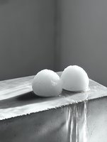 Two white round bath bombs resting on marble surface in monochrome spa setting for relaxation and self-care wellness products.