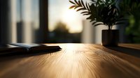 Sunlit wooden desk with open book and potted plant at sunset, creating atmospheric mood with natural light rays and wood grain texture visible on surface.