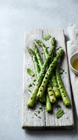 Fresh grilled asparagus spears with herbs on rustic wooden cutting board, healthy spring vegetable dish with olive oil for cooking and nutrition concepts.