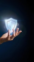 Hand holding glowing shield icon against dark background, representing cybersecurity, data protection, and digital safety for technology and business concepts.
