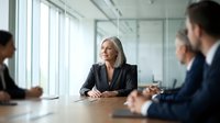 Confident mature businesswoman leading corporate meeting in modern office boardroom with diverse professional team discussing strategy and collaboration.