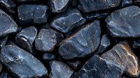 Raw black coal pieces with rough texture and natural mineral formations, showing dark anthracite surface with occasional brown streaks in close-up macro photography.