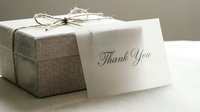 Elegant linen gift box tied with twine beside a handwritten thank you card on a soft neutral background, perfect for gratitude and gifting concepts.