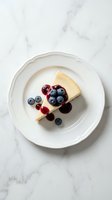 Slice of cheesecake with fresh blueberries and cranberries on white plate over marble surface for dessert menu and bakery advertising.