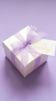 White gift box with lavender organza ribbon and Happy Birthday gold calligraphy tag on purple background, celebration concept.