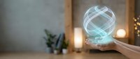 Glowing holographic sphere floating above open palm in modern interior with warm ambient lighting for technology and innovation concepts.