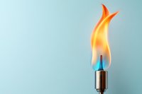 Bright orange and blue flame burning on a metal torch against a soft light blue background, symbolizing heat, energy, and ignition.