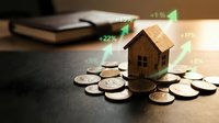 Small wooden house model on coins with rising percentage arrows showing real estate investment growth and property value appreciation concept.