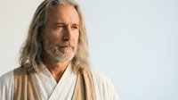 Mature Caucasian man with long gray hair and beard wearing white robe, spiritual teacher or sage portrait on light background for wellness content.
