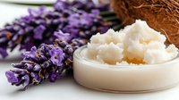 Natural coconut body scrub with fresh lavender flowers on white background, organic spa cosmetics for skincare and aromatherapy treatment.