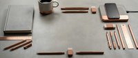 Minimalist workspace flat lay with copper stationery supplies, coffee mug, smartphone and notebook on neutral background for modern office design.