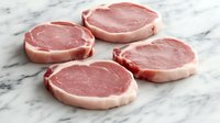 Raw arranged on white marble surface, fresh meat cuts showing natural texture and fat distribution for culinary use.