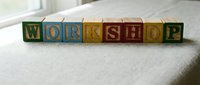 Colorful wooden alphabet blocks spelling WORKSHOP on white fabric surface. Educational toy letters for learning and creative play activities.
