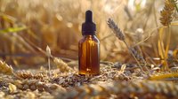 Amber glass dropper bottle with essential oil among dried wheat stalks in golden sunlight, natural aromatherapy and organic skincare concept for wellness products.