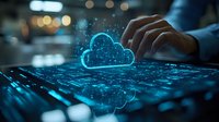 Glowing blue cloud computing icon with digital network connections on laptop keyboard while person types, representing modern technology and data storage.