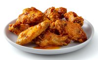 Crispy golden chicken wings glazed with spicy buffalo sauce served on white plate, glistening with savory sauce and ready for appetizer or party snack serving.