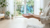 Holographic lungs floating above open palm in bright modern home interior with plants, representing respiratory health and medical technology concepts.