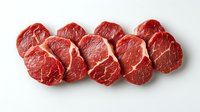 Fresh raw beef tenderloin steaks arranged in row on white background, showing marbling and texture of premium cut meat. Isolated food photography for culinary use.