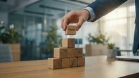 Businessman hand placing wooden block with trust word on pyramid stack in modern office environment representing leadership and business growth strategy.