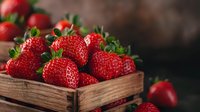 Fresh ripe strawberries in rustic wooden box against dark background, selective focus on juicy red berries with green stems, food photography.
