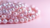 Luxurious pink pearl necklace arranged in elegant curves on soft pink background, creating romantic feminine composition with selective focus and bokeh effect.