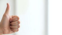 Hand showing thumbs up gesture on white background expressing approval and positive feedback for business success concepts.