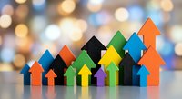 Colorful wooden arrow blocks arranged in ascending pattern showing business growth and success concept with warm bokeh background for presentations.