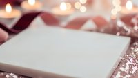 Blank white card with festive ribbon and sparkling lights creating warm holiday atmosphere for greeting cards and seasonal celebrations.