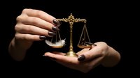 Hands holding golden scales of justice on dark background symbolizing law, legal system, fairness and judicial balance in courtroom proceedings.