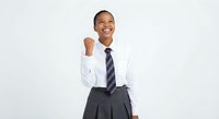 Young African American businesswoman in white shirt and tie celebrating success with raised fist gesture against white background for corporate presentations.