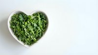Fresh green arugula leaves in heart-shaped white bowl on clean background for healthy eating and nutrition concepts.
