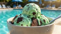 Mint chocolate chip ice cream scoops in bowl by swimming pool on sunny day, perfect for summer dessert and refreshment concepts.