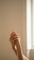 Elegant female hands clasped together in soft natural light by window. Skincare, beauty, wellness and self-care concept for spa and cosmetic advertising.