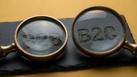 B2B and B2C text visible through magnifying glasses on slate surface against yellow background, representing business models and market segments.