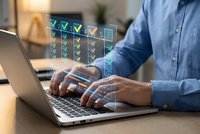 Professional man in blue shirt working on laptop with digital checklist interface overlay showing completed tasks and productivity management system.