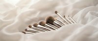 Professional makeup brush set with natural bristles arranged on soft white silk fabric for beauty and cosmetics applications.