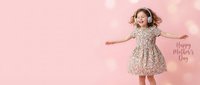 Young girl jumping with joy in floral dress on pink background with bokeh lights and Mother's Day text for greeting cards and celebrations.